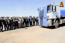 a group of people are standing in front of a large truck with a picture of a man on the side .