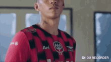 a man with a tattoo on his neck is wearing a red and black soccer jersey .