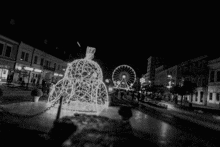 a black and white photo of a ferris wheel in a city at night