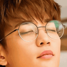 a close up of a person wearing glasses with their eyes closed and their mouth open .