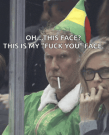 a man with a cigarette in his mouth is wearing a green elf costume