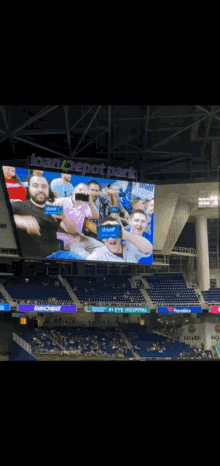 a group of people are posing for a picture in front of a large screen at a baseball game .