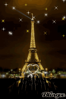 the eiffel tower is lit up at night with a heart in the middle of it