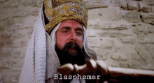 a man with a beard and a crown has blasphemer written on his forehead