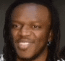 a close up of a man 's face with dreadlocks smiling