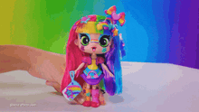 a person is holding a doll with a rainbow hairdo