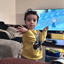 a little boy standing in front of a television with a toy police car in front of him