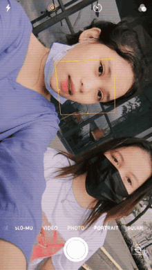 two girls wearing face masks are taking a selfie with their phone