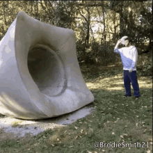 a man throws a frisbee in front of a large concrete sculpture with the name brodiesmith21 written on the bottom