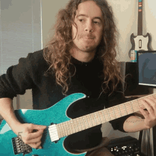 a man with long curly hair is playing a blue electric guitar
