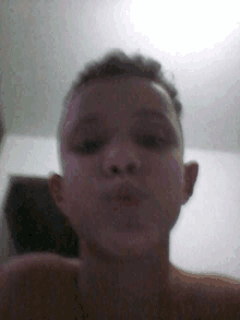 a young boy without a shirt is taking a selfie in a dark room .