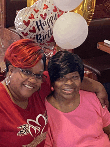 two women posing for a picture with a happy birthday balloon