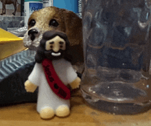 a small figurine of jesus with a red sash around his neck is next to a dog