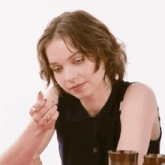 a woman is sitting at a table with two glasses in front of her and looking at the camera .