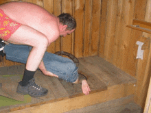 a man squatting on another man 's feet in a wooden shed