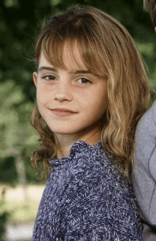 a young girl in a blue sweater is standing next to a boy .