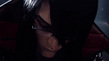 a close up of a person 's face in a dark room with a red cape .