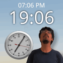 a man with glasses stands in front of a clock that says 19:06