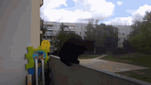 a black cat is sitting on a balcony next to a smiley face toy