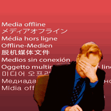 a man in a suit and tie covering his face with his hand in front of a red background that says media offline