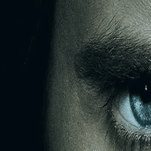 a close up of a person 's blue eye with tears coming out of it .