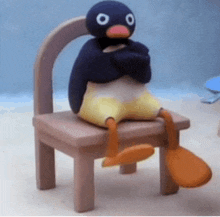 a stuffed penguin is sitting on a chair