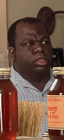 a man is standing in front of jars of honey and sticks