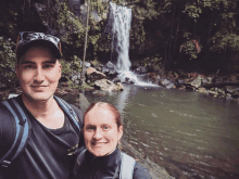 a man and a woman standing in front of a waterfall with the man wearing a shirt that says nike on it