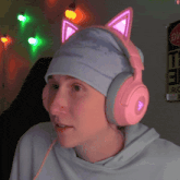 a person wearing pink headphones and a hat with cat ears on it