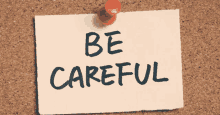 a note pinned to a cork board says be careful