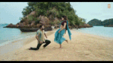 a man is squatting down next to a woman on a beach .