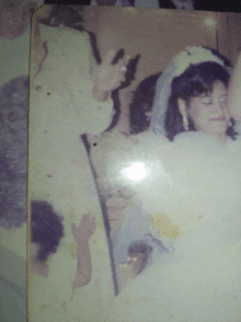 a bride in a white wedding dress is surrounded by a group of people