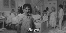 a black and white photo of a little girl standing in front of a group of children in a room .