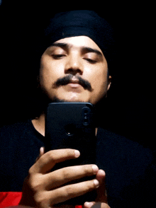 a man wearing a turban is taking a picture of himself with his phone