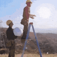 a man in a hard hat is standing on a ladder while another man stands behind him holding a bucket .