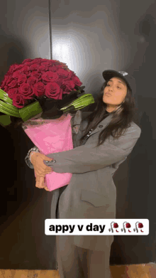 a woman holding a large bouquet of red roses with appy v day written on the bottom