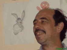 a man is smiling in front of a drawing of a donkey on a wall