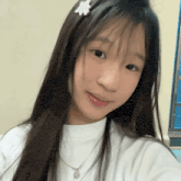a young girl is taking a selfie with a flower in her hair and a necklace .