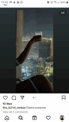 a phone screen shows a person holding a glass in front of a building