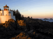 a lighthouse sits on top of a rocky hill overlooking the ocean