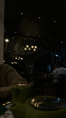 a green teapot sits on a table in front of a dark restaurant