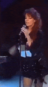 a woman is singing into a microphone while standing on a stage .