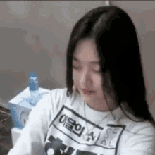 a woman wearing a white t-shirt with chinese writing on it is sitting at a table .