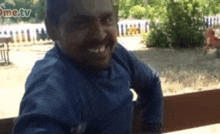 a man in a blue shirt is smiling in front of a sign that says home tv