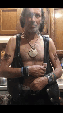 a man wearing a leather vest has a sand dollar necklace around his neck