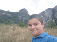 a young boy is standing in a field with mountains in the background .