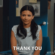 a woman is sitting in front of a blue door with the words thank you on the bottom