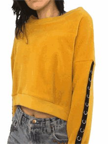 a woman wearing a yellow sweatshirt with black lace up sleeves