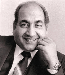 a black and white photo of a man in a suit and tie smiling with his hand on his chin .