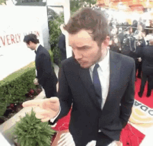 a man in a suit and tie is standing on a red carpet in front of a sign that says beverly hills